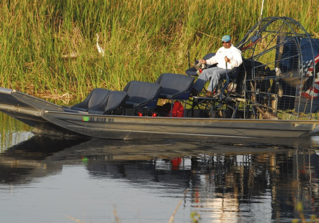 a boat operator manning an airboat in the middle of a wetland