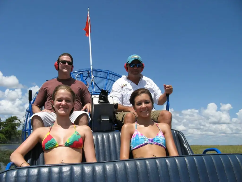 Guests enjoying a private Everglades airboat ride with Captain Randy at the helm, exploring the open marsh under clear South Florida skies.