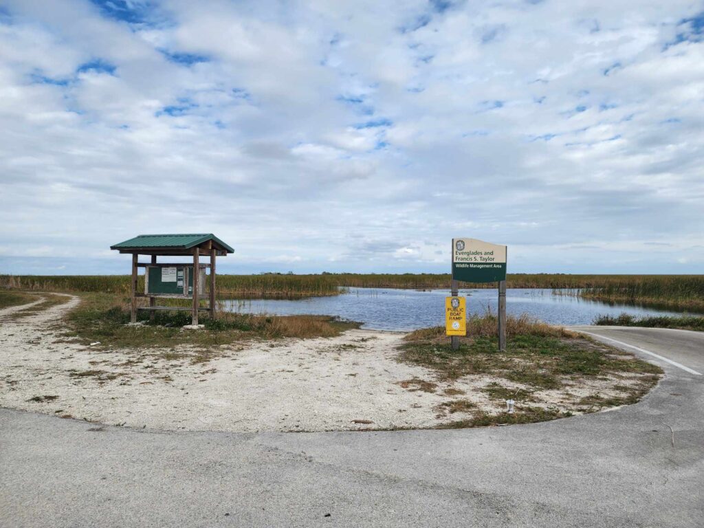 Entrance to the Everglades and Francis S. Taylor Wildlife Management Area, showcasing the vast wetlands and public boat ramp under a partly cloudy sky